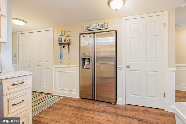 kitchen with light hardwood / wood-style flooring, light stone countertops, and stainless steel refrigerator with ice dispenser