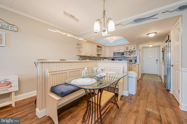 dining area featuring a raised ceiling, crown molding, and hardwood / wood-style floors