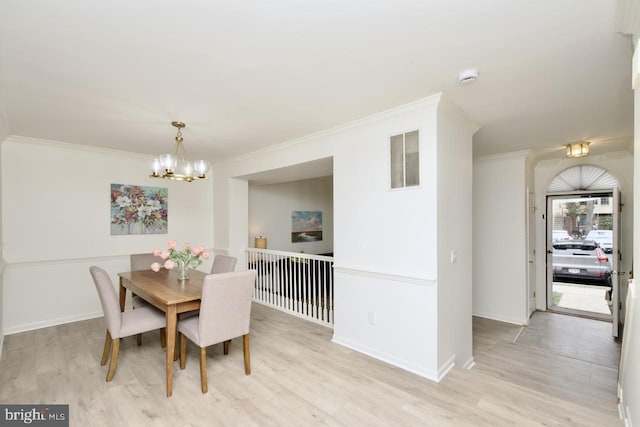 dining room with a notable chandelier, light wood-style flooring, and crown molding