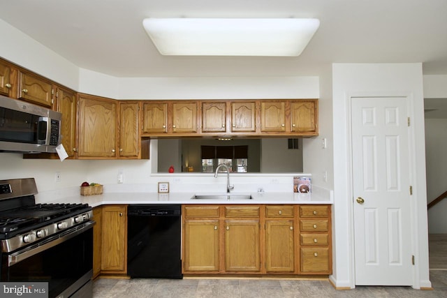 kitchen featuring brown cabinetry, appliances with stainless steel finishes, light countertops, and a sink