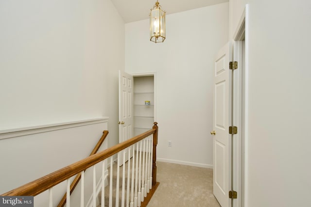 corridor featuring baseboards, an upstairs landing, and light colored carpet