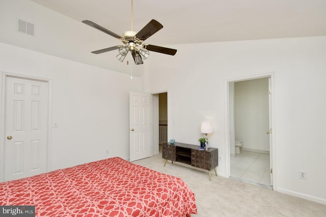 carpeted bedroom featuring ceiling fan, visible vents, baseboards, and ensuite bath