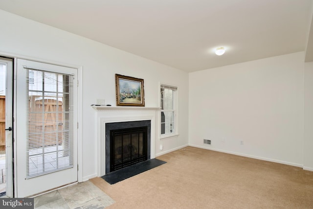 unfurnished living room featuring baseboards, visible vents, a fireplace with flush hearth, and light carpet