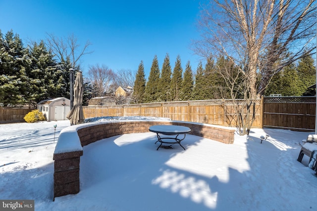 snow covered patio featuring a storage shed