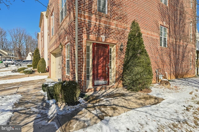 snow covered property entrance featuring a garage