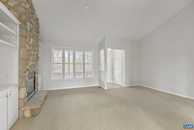 unfurnished living room with lofted ceiling, a fireplace, and light carpet