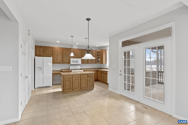 kitchen with light tile patterned floors, white appliances, decorative light fixtures, and a kitchen island