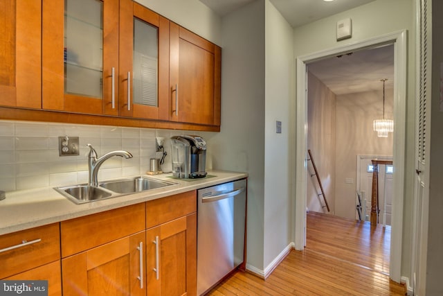 kitchen with dishwasher, decorative backsplash, sink, light hardwood / wood-style flooring, and hanging light fixtures