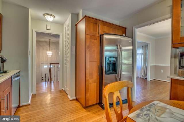 kitchen with an inviting chandelier, stainless steel appliances, crown molding, and light hardwood / wood-style floors