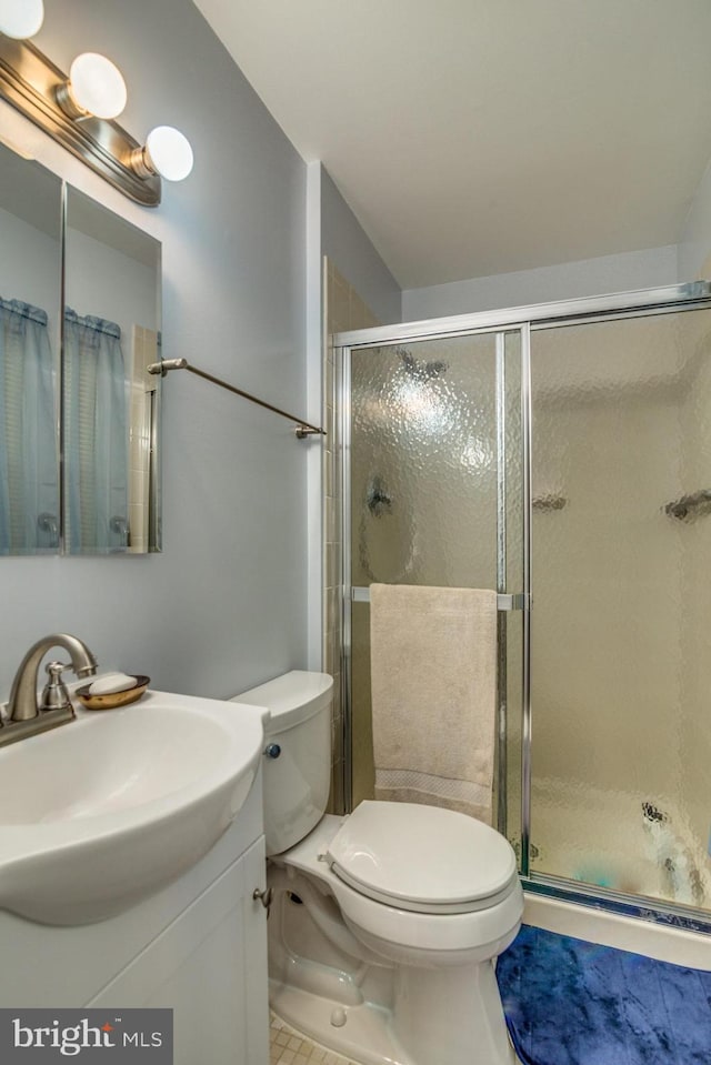 bathroom with toilet, vanity, and a shower with shower door