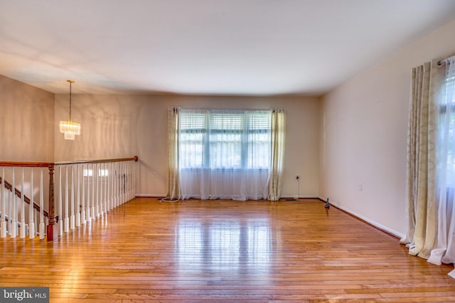 empty room with a chandelier and light hardwood / wood-style floors