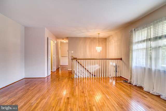 unfurnished room with an inviting chandelier and hardwood / wood-style flooring