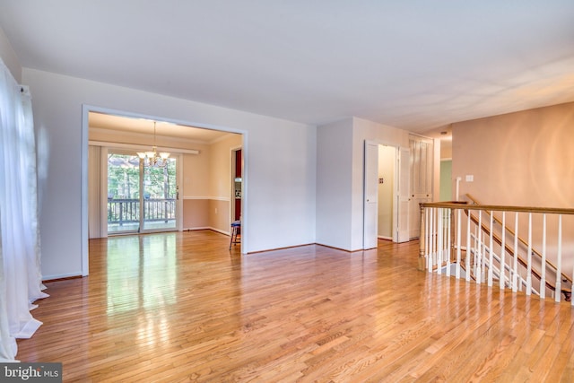 empty room with hardwood / wood-style flooring and a notable chandelier