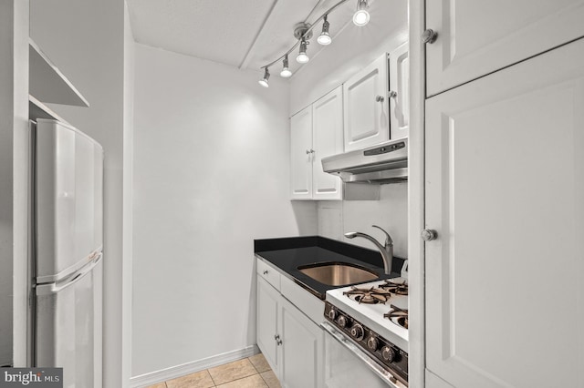 kitchen with white cabinets, sink, white gas range oven, fridge, and light tile patterned floors