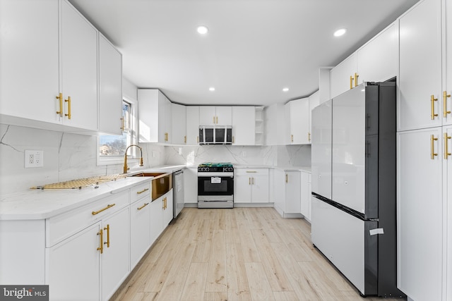 kitchen featuring white cabinets, stove, sink, and white fridge