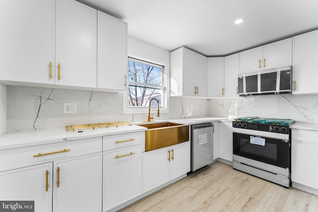 kitchen featuring white cabinets, dishwasher, sink, backsplash, and stove