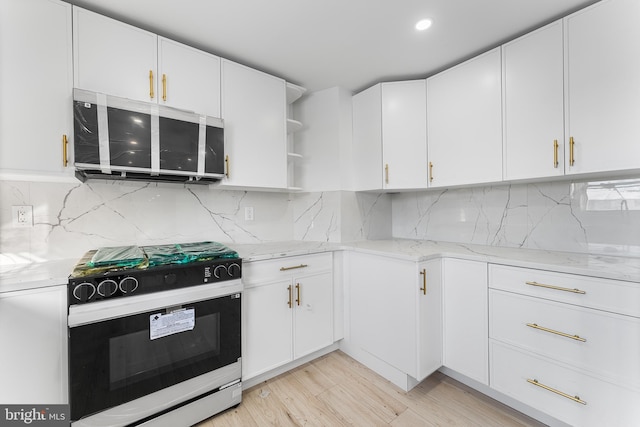 kitchen with black stove, light stone countertops, white cabinetry, and decorative backsplash