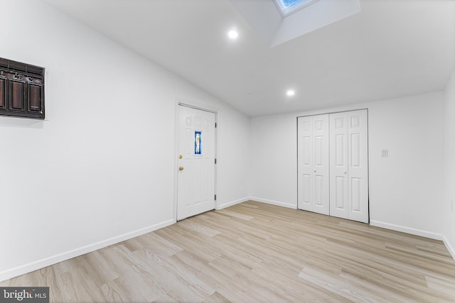 foyer entrance featuring vaulted ceiling with skylight and light hardwood / wood-style floors