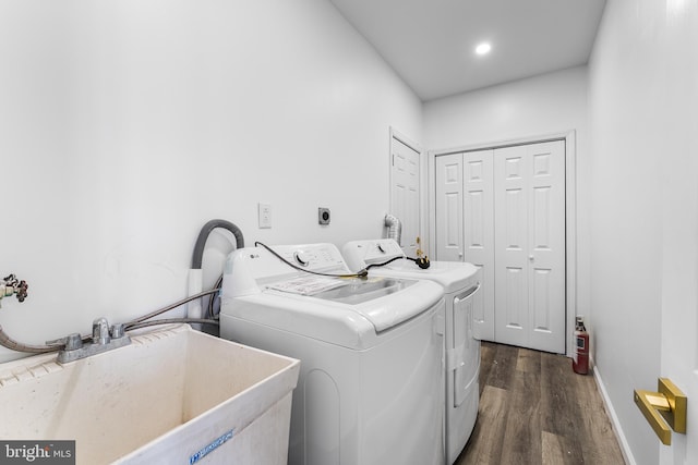 washroom with dark wood-type flooring, sink, and washing machine and clothes dryer