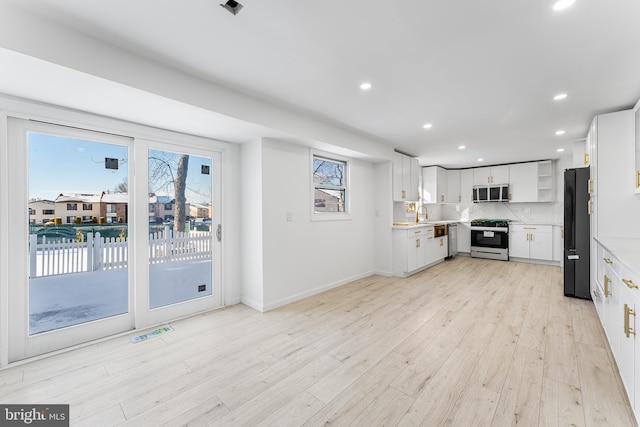 kitchen featuring backsplash, light hardwood / wood-style floors, sink, white cabinetry, and stainless steel appliances