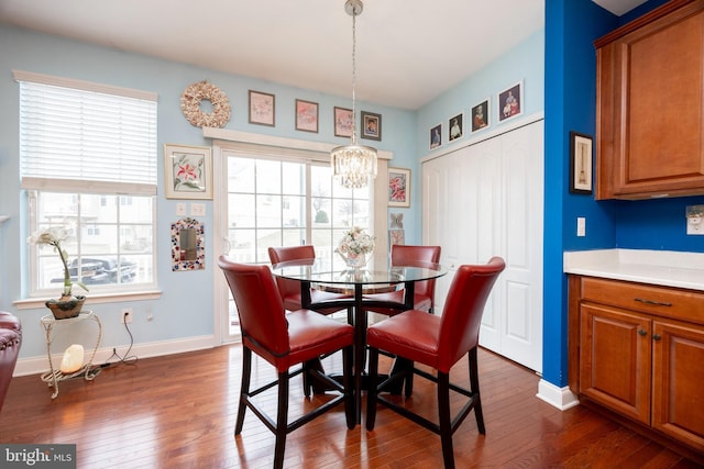 dining area with a wealth of natural light, dark hardwood / wood-style flooring, and a notable chandelier