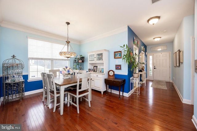 dining room with dark hardwood / wood-style flooring, crown molding, and a chandelier