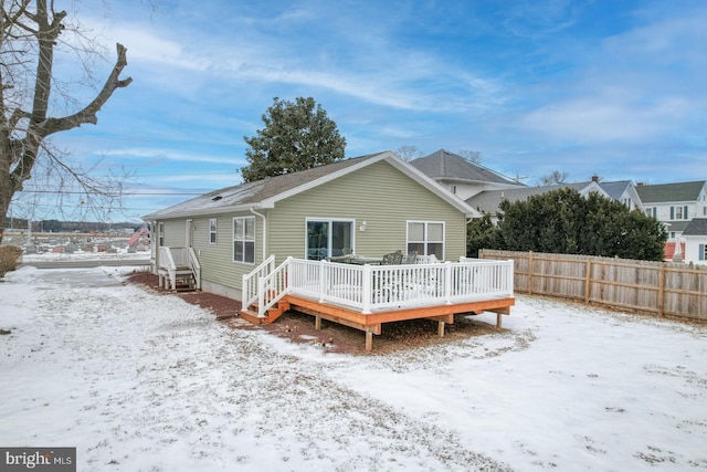 snow covered rear of property with a deck