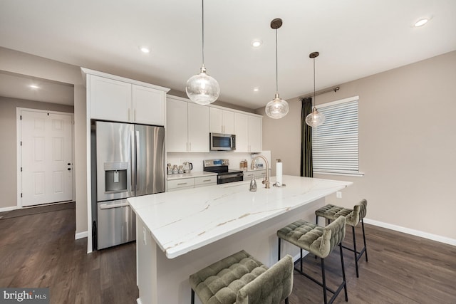 kitchen with a center island with sink, appliances with stainless steel finishes, white cabinets, and hanging light fixtures