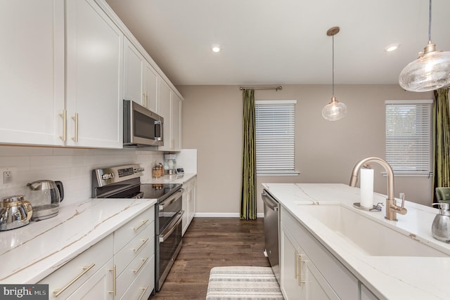 kitchen with appliances with stainless steel finishes, sink, pendant lighting, and white cabinets