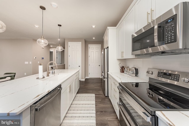 kitchen featuring appliances with stainless steel finishes, sink, white cabinets, decorative backsplash, and hanging light fixtures