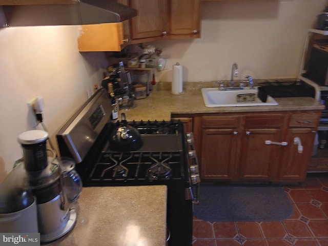 kitchen with exhaust hood, stainless steel gas stove, dark tile patterned flooring, and sink