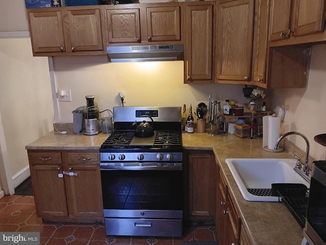 kitchen featuring sink, dark tile patterned flooring, and stainless steel gas range oven