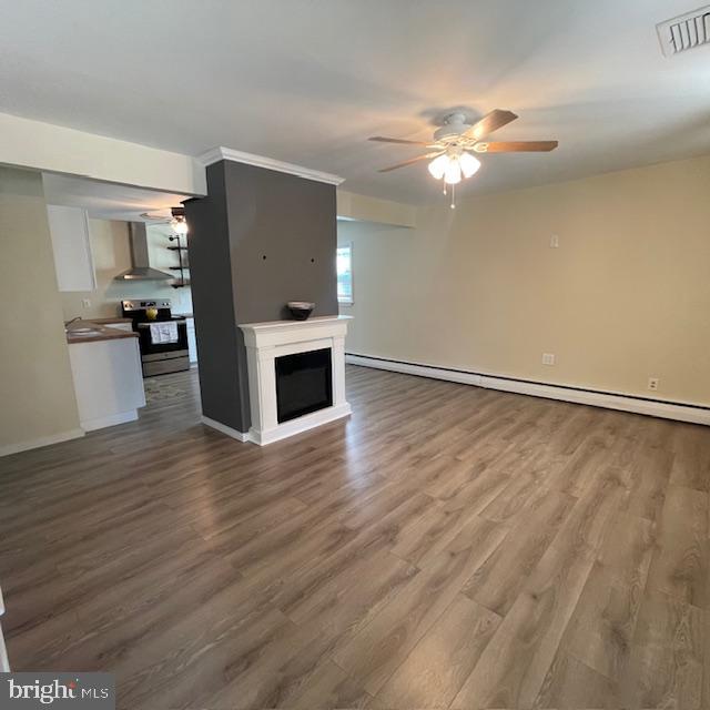 unfurnished living room with ceiling fan, wood-type flooring, and a baseboard radiator