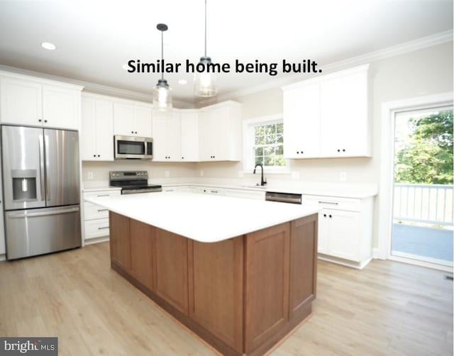 kitchen with appliances with stainless steel finishes, hanging light fixtures, a kitchen island, and white cabinets