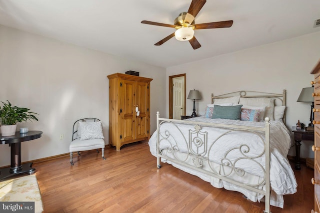 bedroom with baseboards, a ceiling fan, visible vents, and light wood-style floors