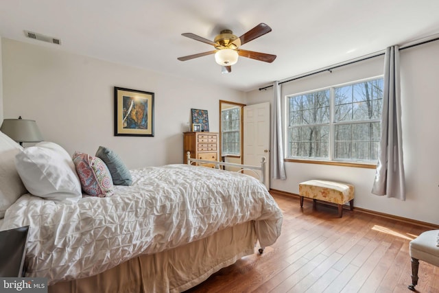 bedroom with visible vents, ceiling fan, baseboards, and hardwood / wood-style flooring