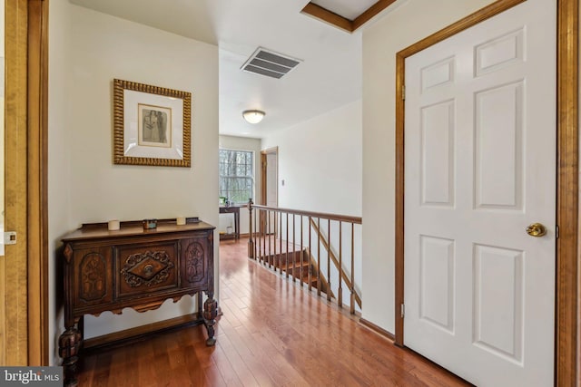 hall with hardwood / wood-style floors, an upstairs landing, visible vents, and baseboards