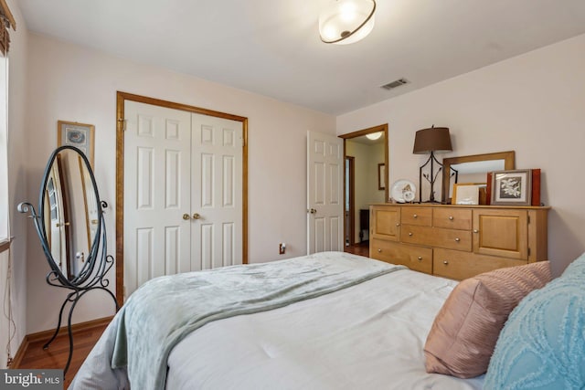 bedroom with baseboards, visible vents, a closet, and wood finished floors