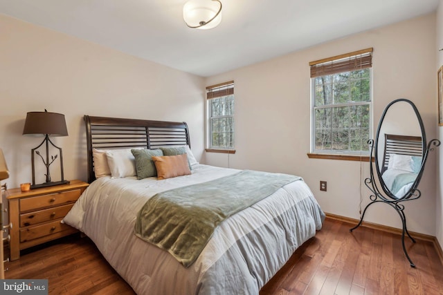 bedroom with multiple windows, hardwood / wood-style flooring, and baseboards