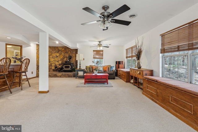 living room featuring a wood stove, visible vents, and light colored carpet