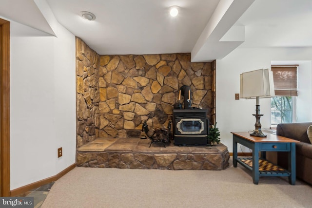 living room featuring a wood stove, baseboards, and carpet flooring