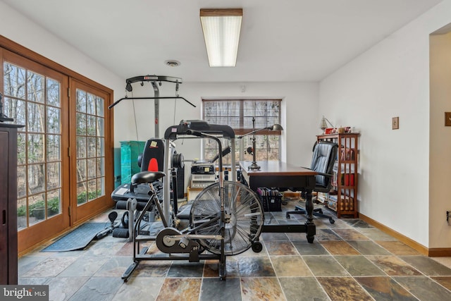 exercise room with baseboards, visible vents, and stone tile floors