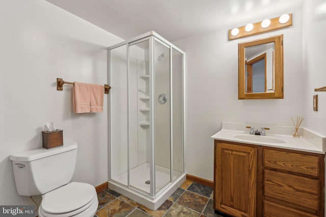 bathroom with toilet, a stall shower, stone tile floors, and vanity