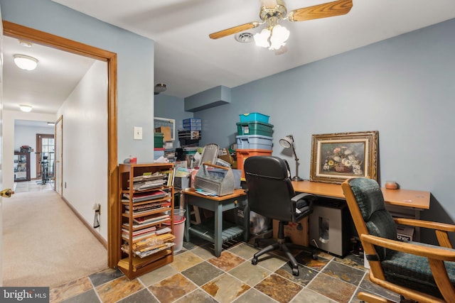 office area with stone finish flooring, a ceiling fan, and baseboards