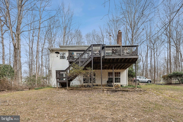 back of property featuring a chimney, a wooden deck, and stairs