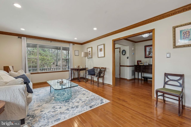 living area with baseboards, recessed lighting, wood finished floors, and crown molding