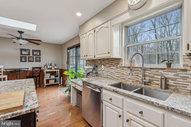 kitchen featuring a sink, light stone counters, white cabinets, and dishwasher