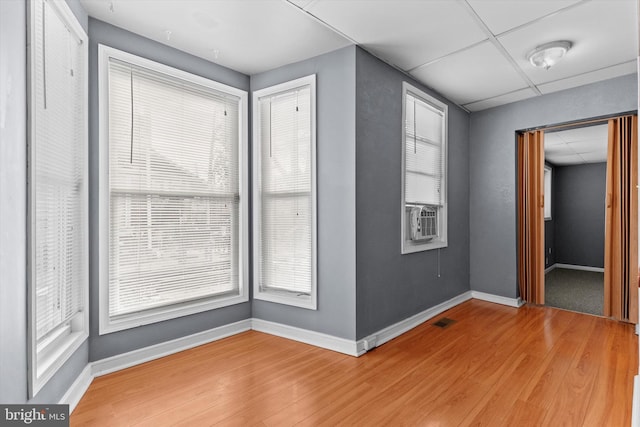 spare room with a drop ceiling, cooling unit, and hardwood / wood-style flooring