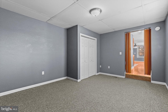 unfurnished bedroom featuring a drop ceiling, a closet, and carpet flooring