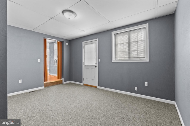 carpeted empty room featuring a drop ceiling